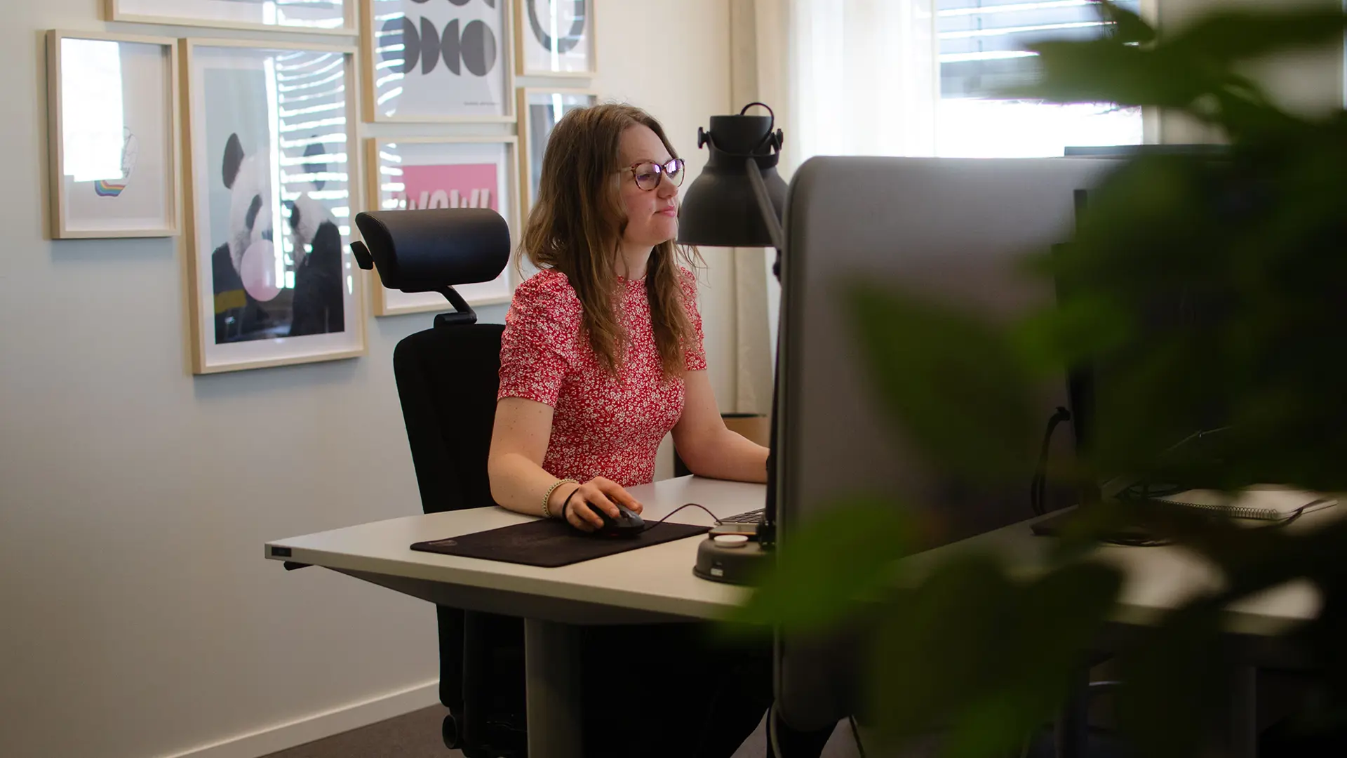 Kvinna med röd tröja sittandes framför en dator