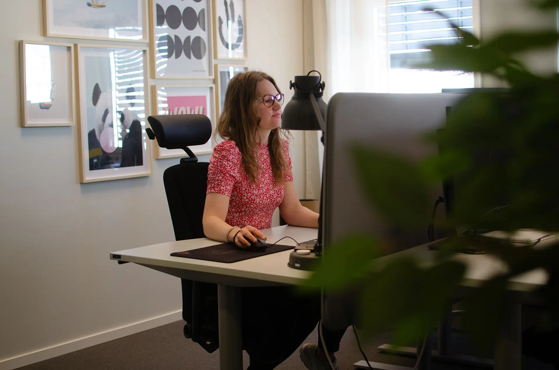 Kvinna med röd tröja sittandes framför en dator