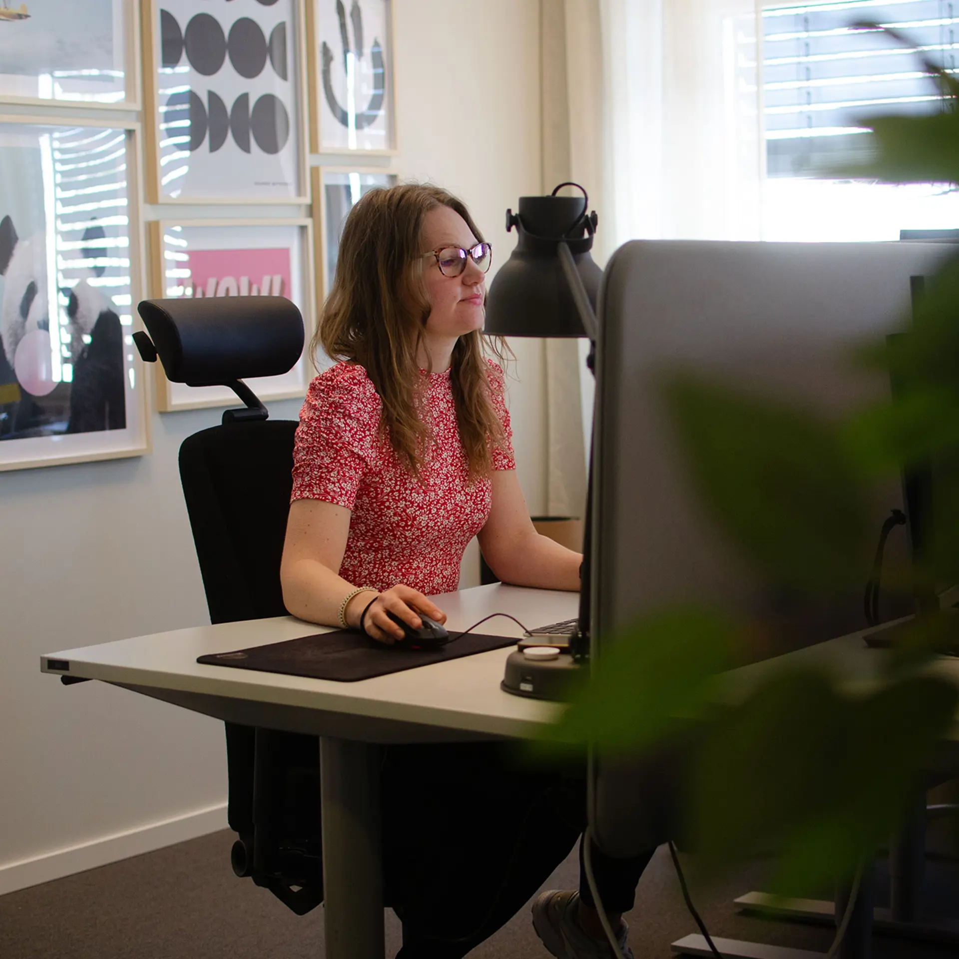 Kvinna med röd tröja sittandes framför en dator