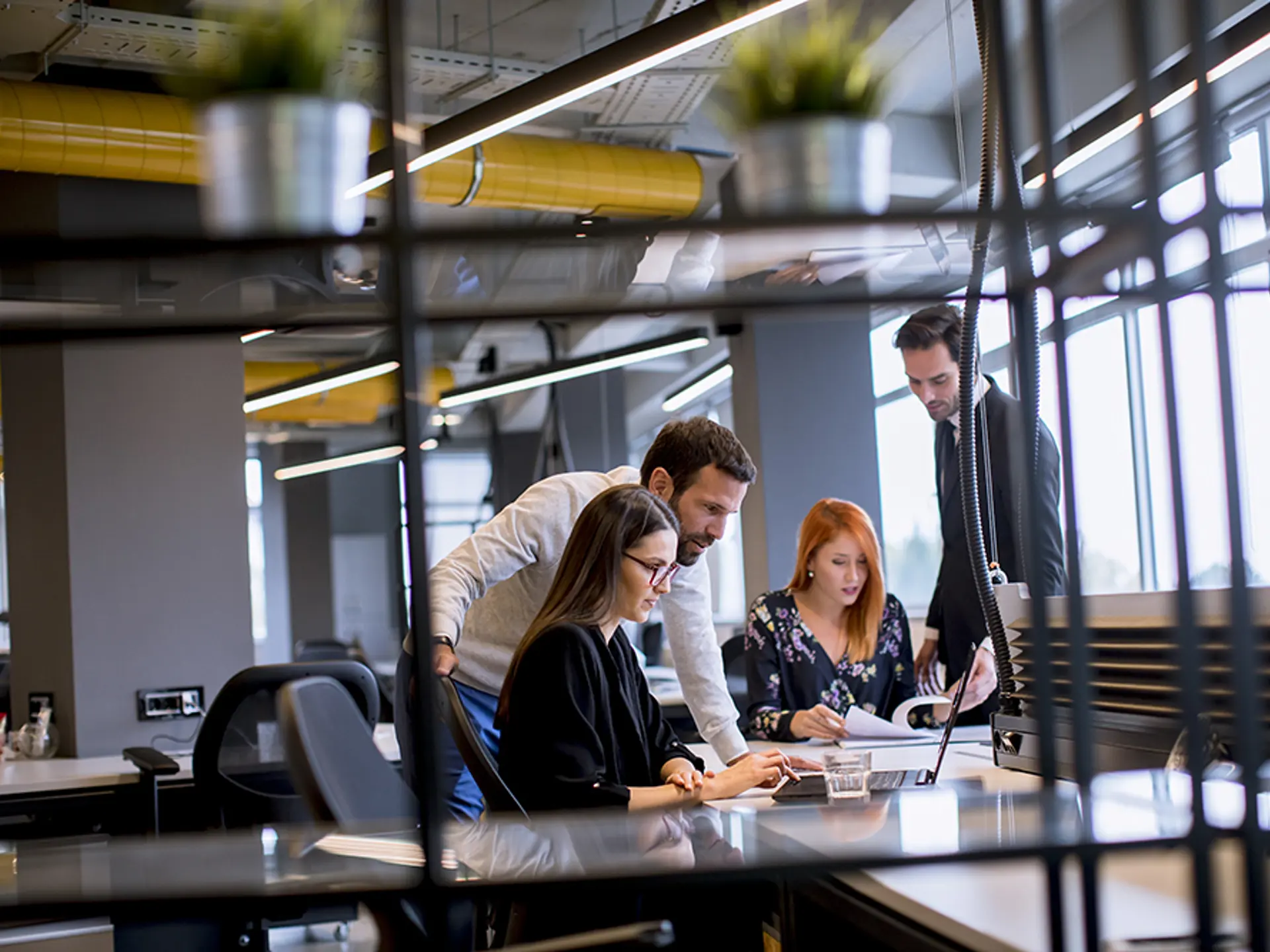 Fyra personer som står framför en dator och jobbar tillsammans