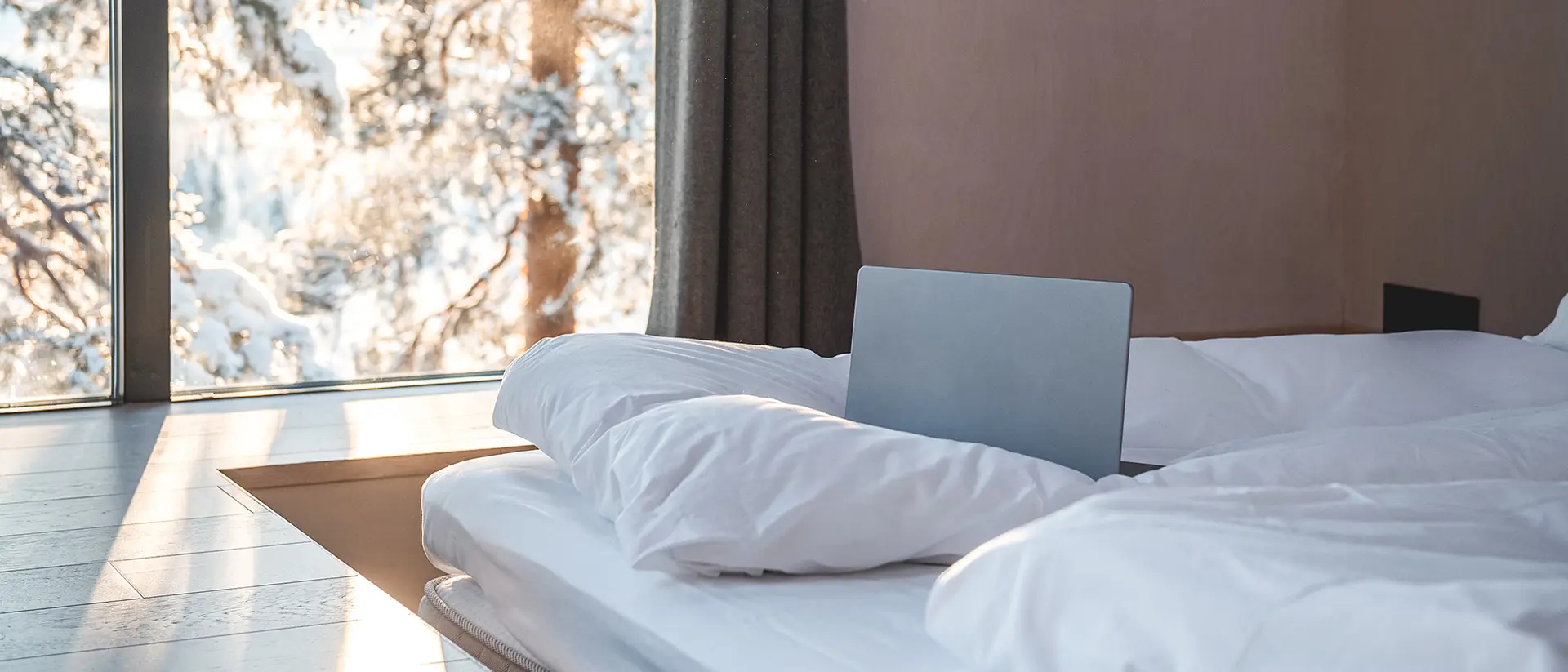 Sängar med vita påslakan och en laptop stående i sängen