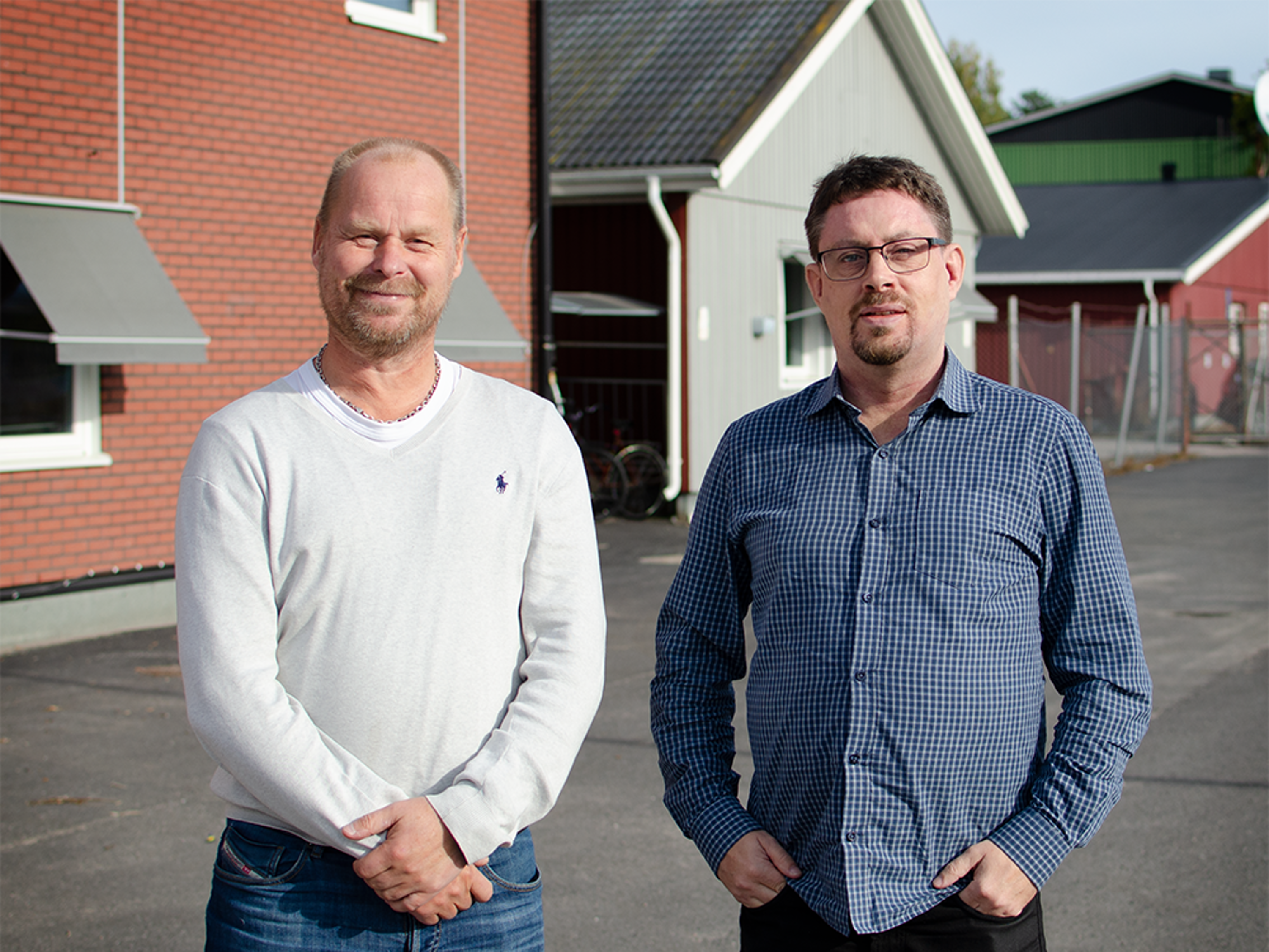 Två män som står bredvid varandra framför ett hus