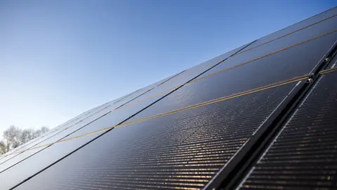 Solpaneler på tak och i bakgrunden en blå himmel