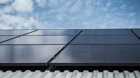 Solpaneler på tak och i bakgrunden en blå himmel