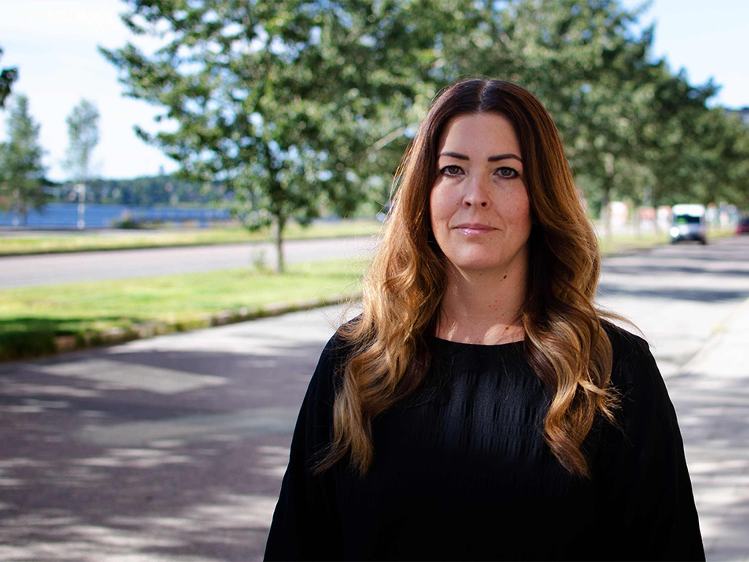 Kvinna med långt brunt hår som står ute vid en väg