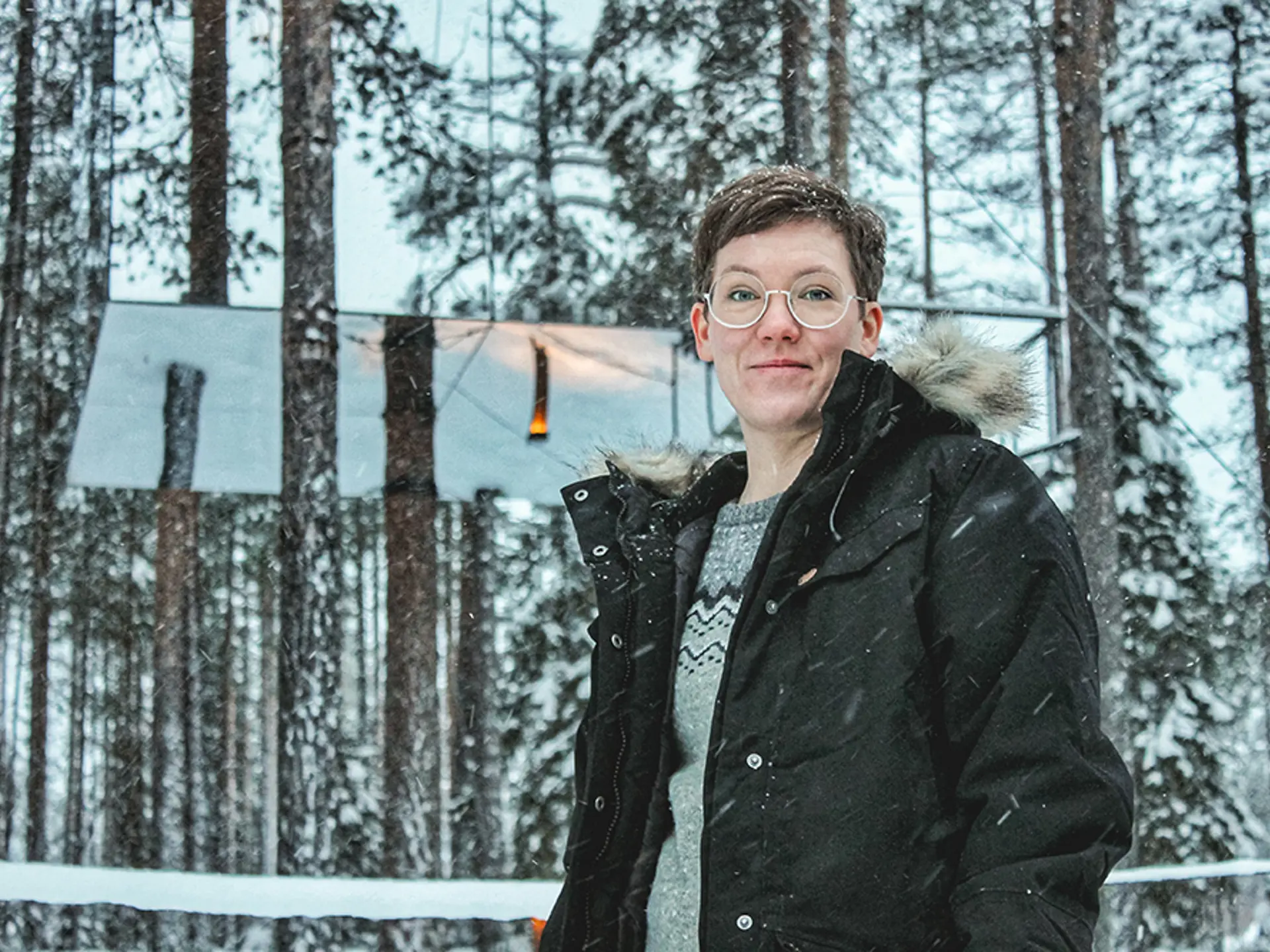 Kvinna som tittar in i kameran, det snöar ute.